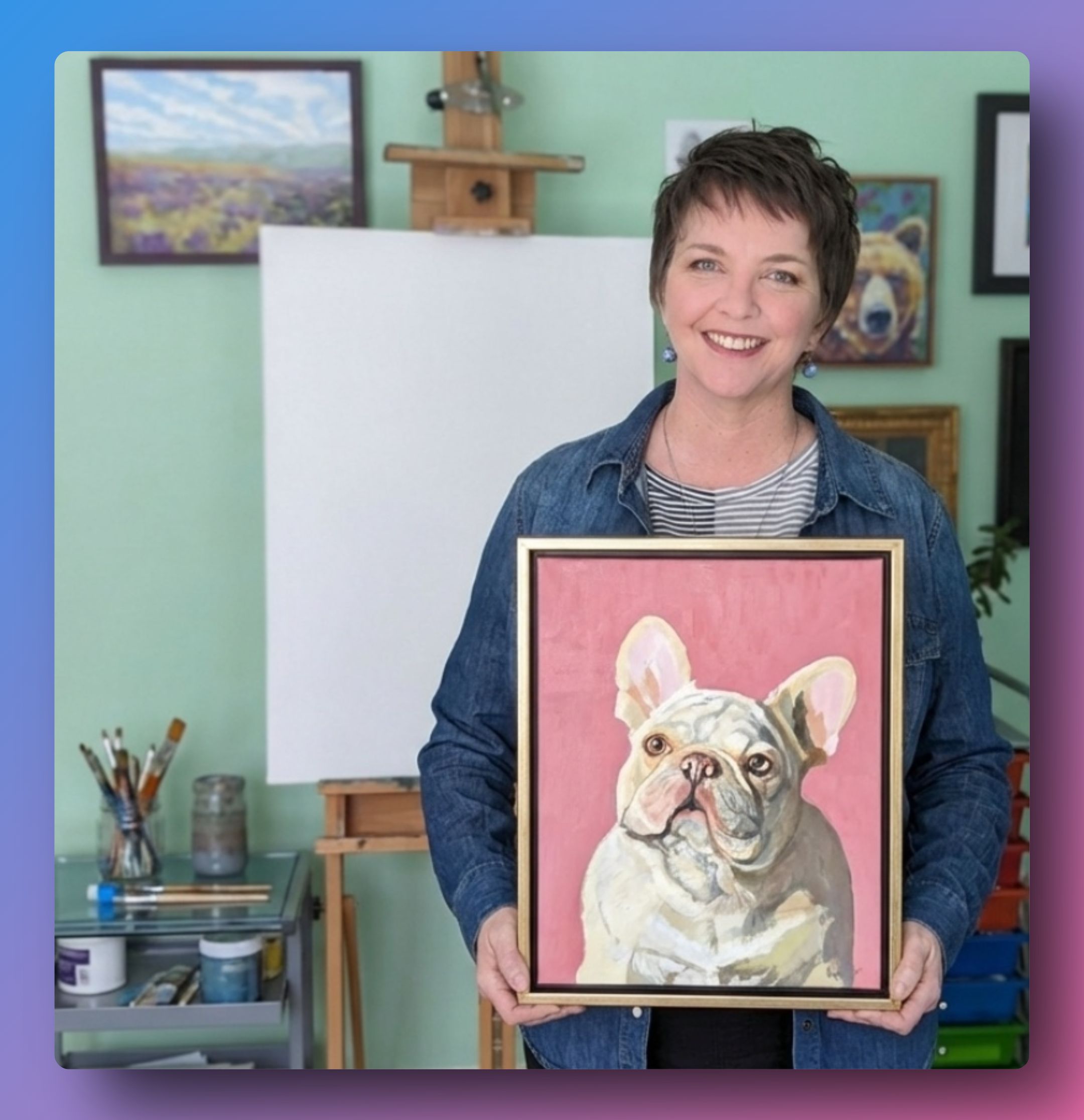 Pet portrait artist in studio holding French Bulldog painting